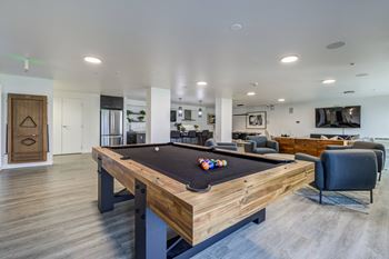 A pool table is in the middle of a room with a chair and a couch.